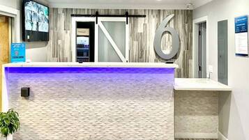 A reception desk with a modern design, a large number '6' sign, and a television mounted on the wall.