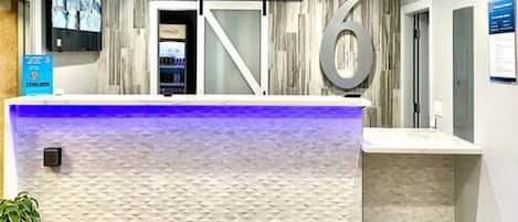 Una reception dal design moderno, un grande cartello con il numero '6' e un televisore montato a parete.