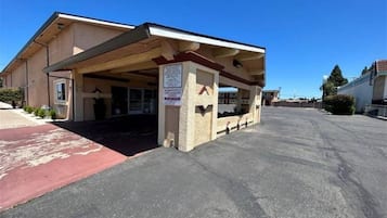 Un bâtiment doté d’une entrée abritée, d’une enseigne et d’un parking.