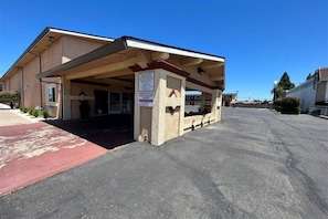 A building with a covered entrance, a signboard, and a parking lot.