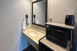 Une salle de bain équipée d’un lavabo, d’un miroir, d’un porte-serviettes et d’un haut-parleur noir posé sur le comptoir.