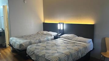 A hotel room with two beds, a bedside table, and a chair.