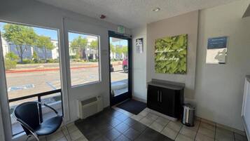 A reception area with a chair, a cabinet, and a trash bin.