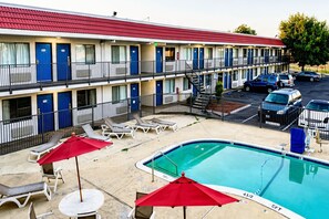A motel with a swimming pool, outdoor seating, and a parking area. - 2 Full Beds|NS | Modesto (Modesto)