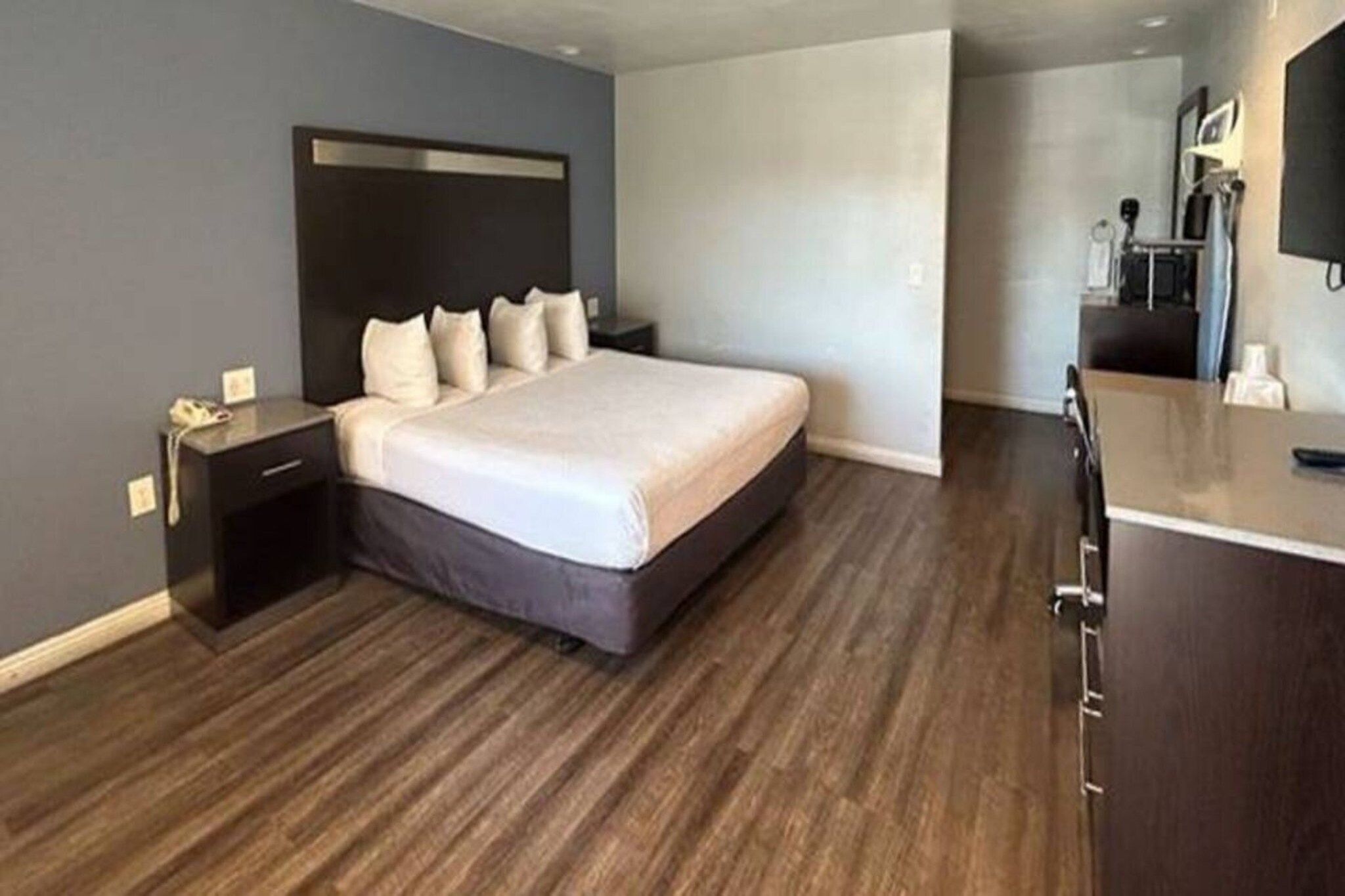 Ein Hotelzimmer mit Bett, Nachttisch, Kommode und Spiegel.