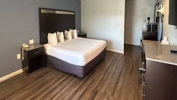 Een hotelkamer met een bed, nachtkastje, dressoir en spiegel.
