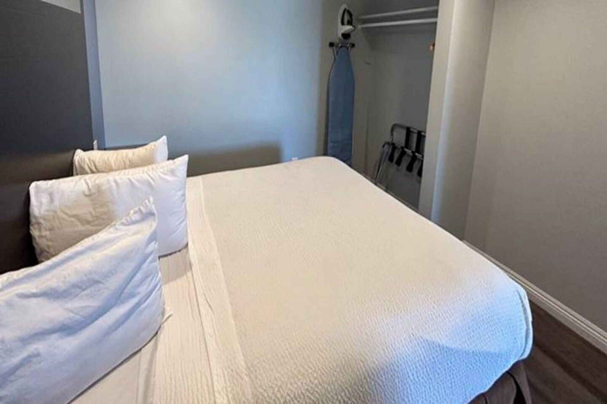 Een hotelkamer met een bed, kussens, een kledingkast en een handdoekhouder.
