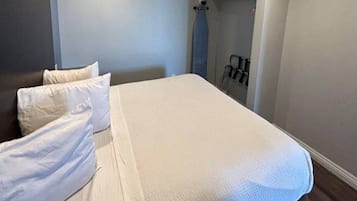 Een hotelkamer met een bed, kussens, een kledingkast en een handdoekhouder.