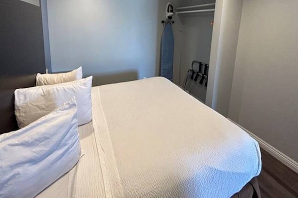 Een hotelkamer met een bed, kussens, een kledingkast en een handdoekhouder.