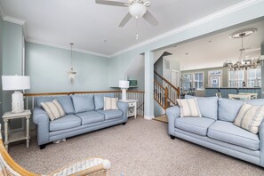 Ein Wohnzimmer mit zwei Sofas, einer Chandelüster und einem Deckenventilator.