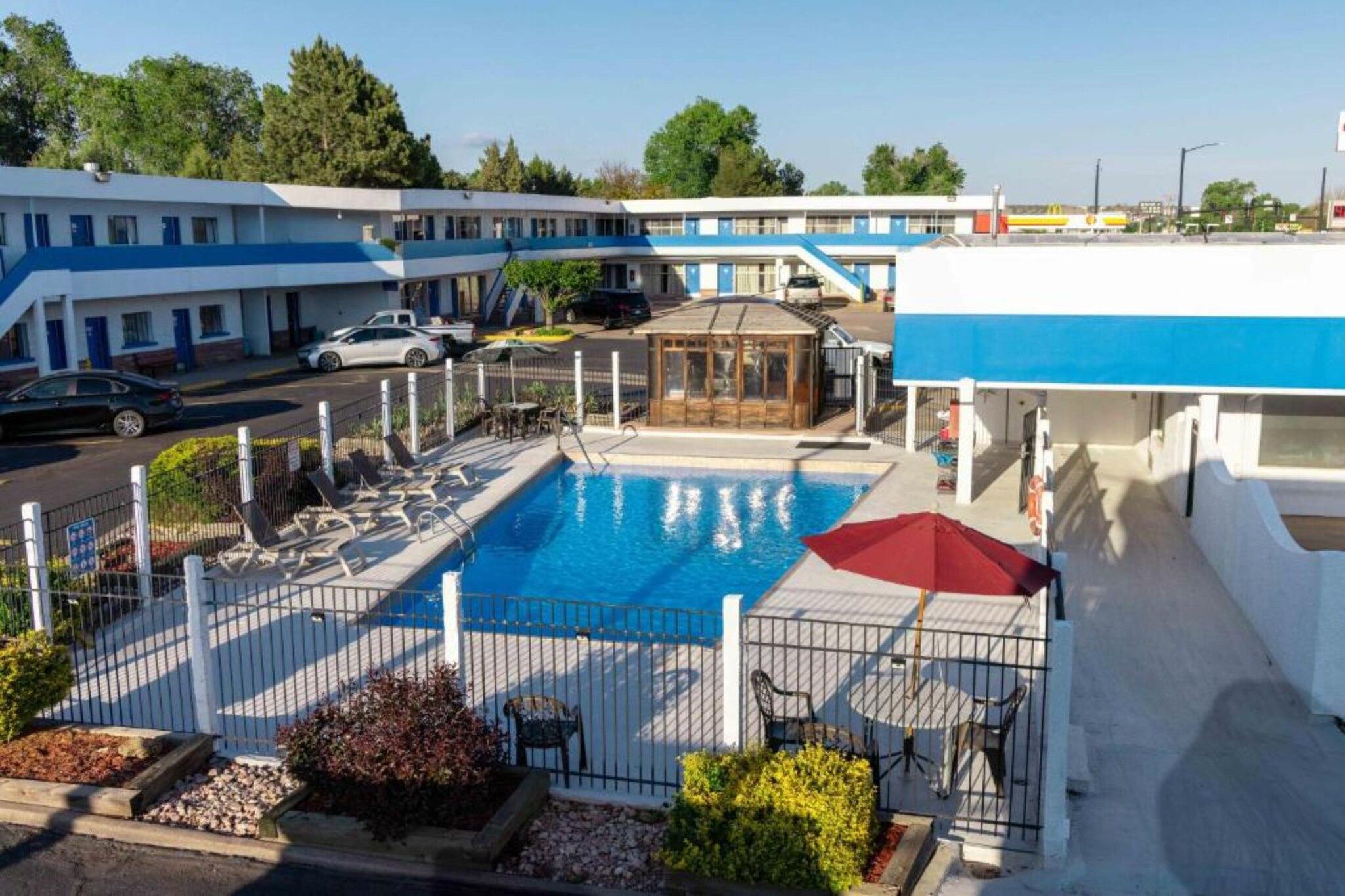 A hotel with a swimming pool, outdoor seating, and a view of the street.