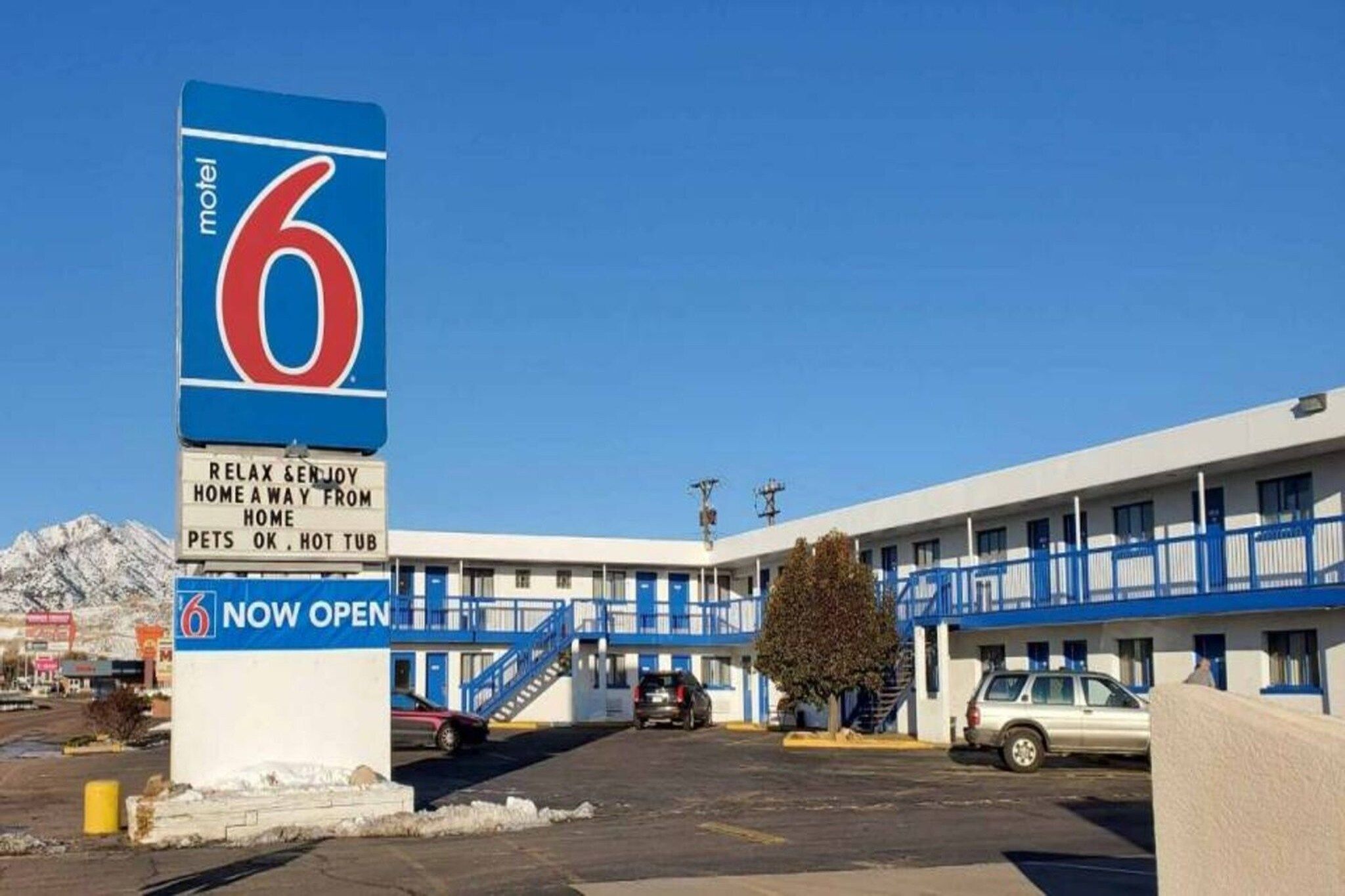 A motel with a large sign indicating it is now open, featuring a number 6 and a pet-friendly message.