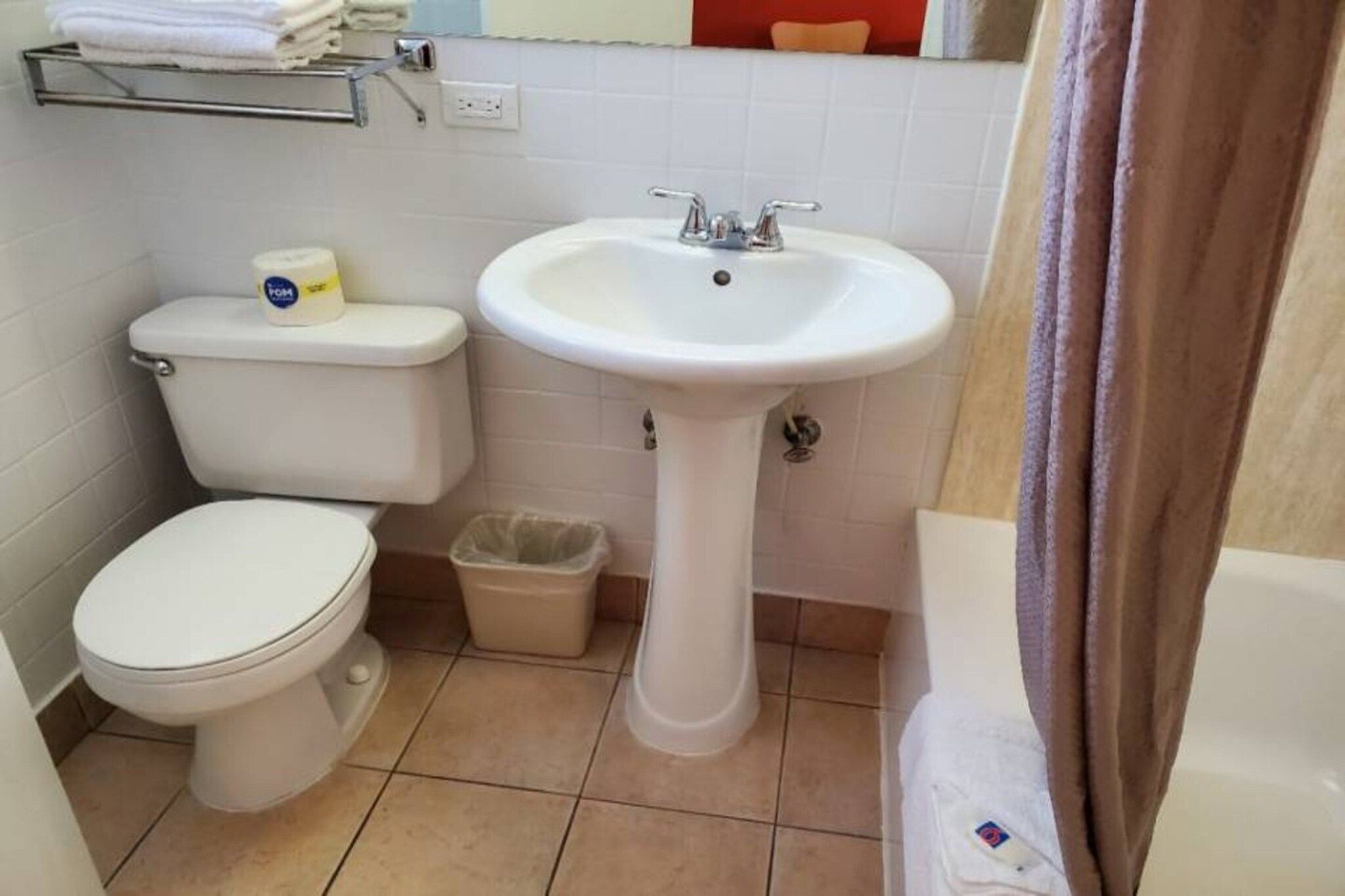 A small bathroom with a toilet, a sink, and a trash bin.