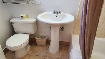 A small bathroom with a toilet, a sink, and a trash bin.