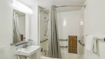 A bathroom with a bathtub, a shower, a sink, and a mirror.