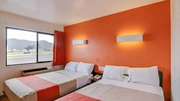 Een hotelkamer met twee bedden, een raam met uitzicht en een wandlamp.
