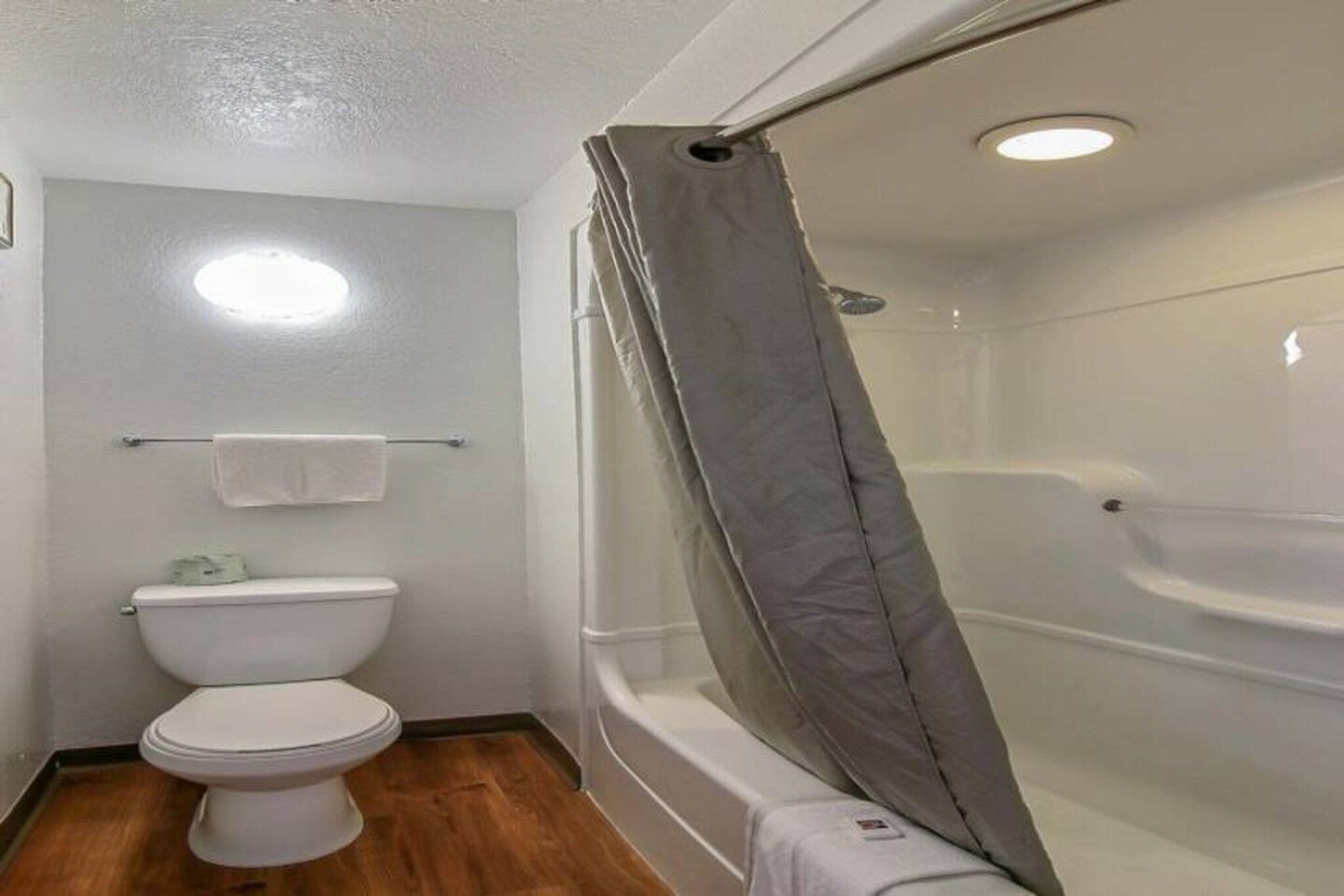 Une salle de bain comprenant des toilettes, une douche avec un rideau et un porte-serviettes.