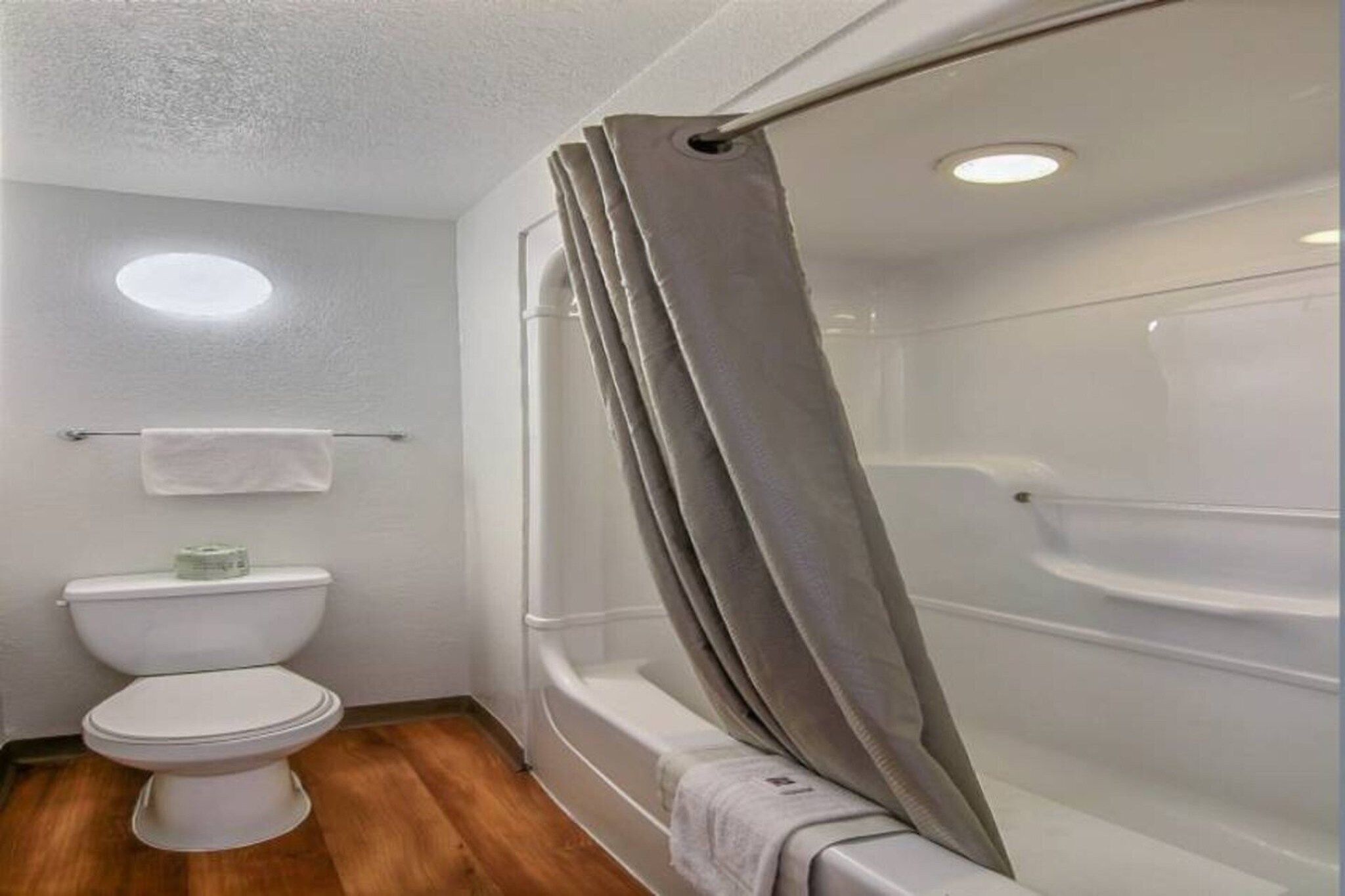 A bathroom with a toilet, a shower with a curtain, and a towel rack.