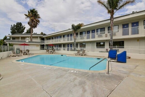 Un hôtel doté d’une piscine, d’un espace extérieur aménagé et d’un immeuble à plusieurs étages avec des balcons.