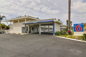 A motel with a blue and white exterior, a covered parking area, and a sign indicating the motel number 6. - Comfy Queen Beds|Free Wifi&Parking (Buellton)