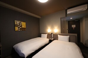 Habitación de hotel con dos camas, un cuadro en la pared y un equipo de aire acondicionado.