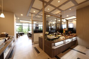 A modern hotel lobby with a buffet area, wooden flooring, and large windows.