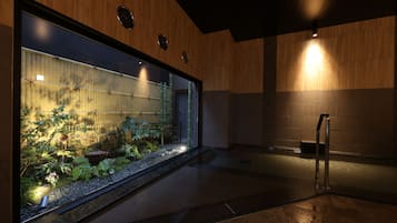 En modern inredning med ett stort akvarium, väggar beklädda med träpaneler och en spiraltrappa i metall.