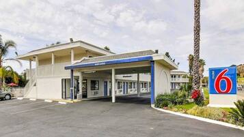 A motel with a gas station, a covered parking area, and a sign indicating the motel number.