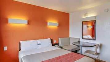 Een hotelkamer met een bed, een bureau, een stoel en een spiegel.