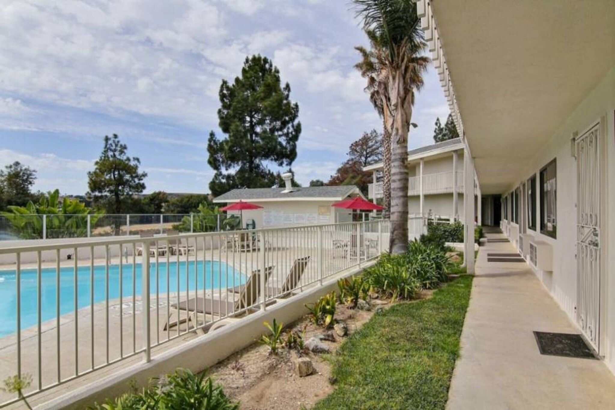 A hotel with a swimming pool, a covered patio area, and a view of the surrounding landscape.