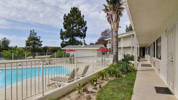 A hotel with a swimming pool, a covered patio area, and a view of the surrounding landscape.