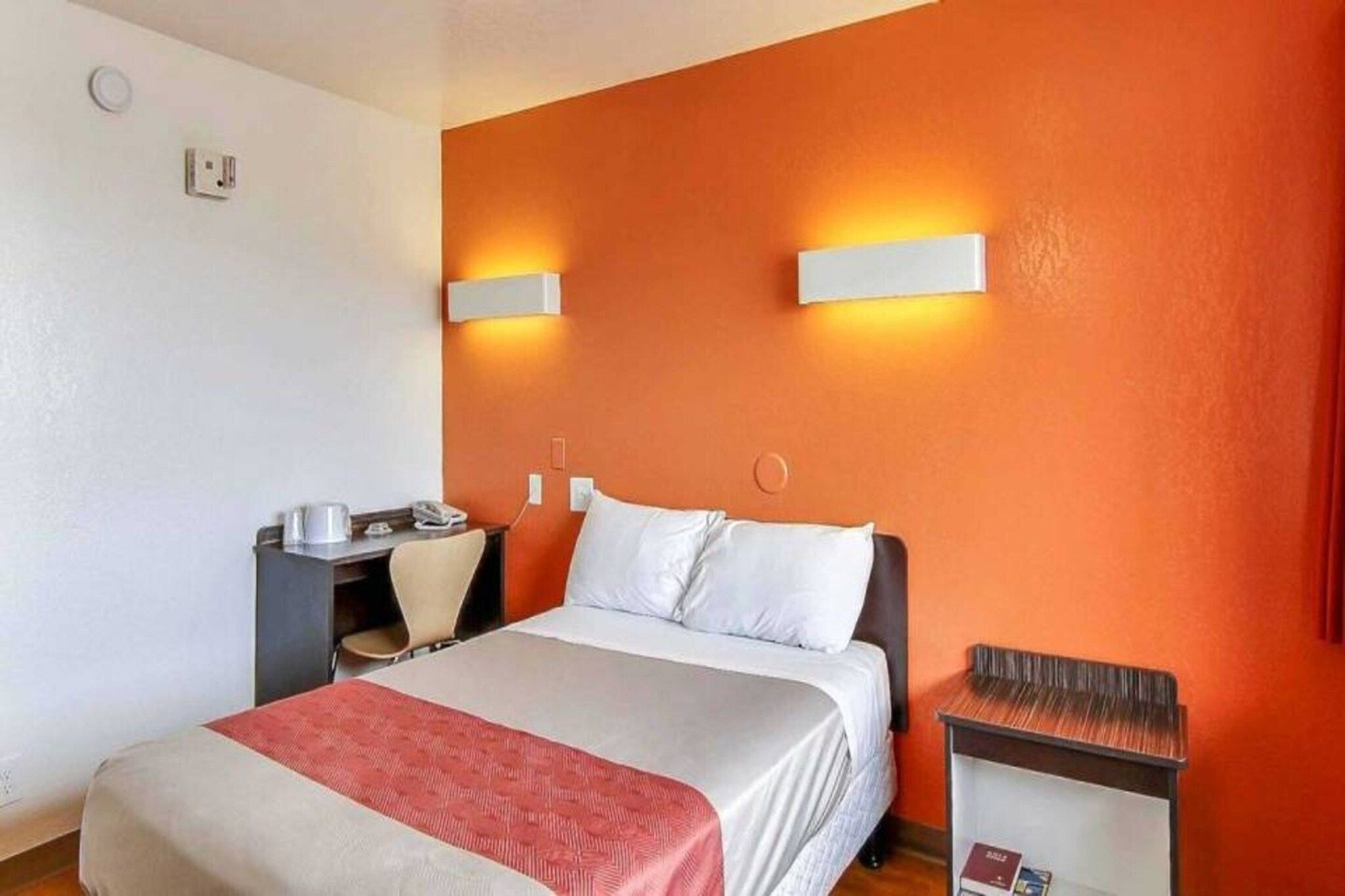 A hotel room with a bed, a desk, and a chair.