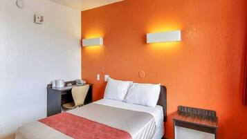 A hotel room with a bed, a desk, and a chair.