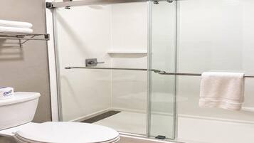A modern bathroom with a glass-enclosed shower, a toilet, and a towel rack.