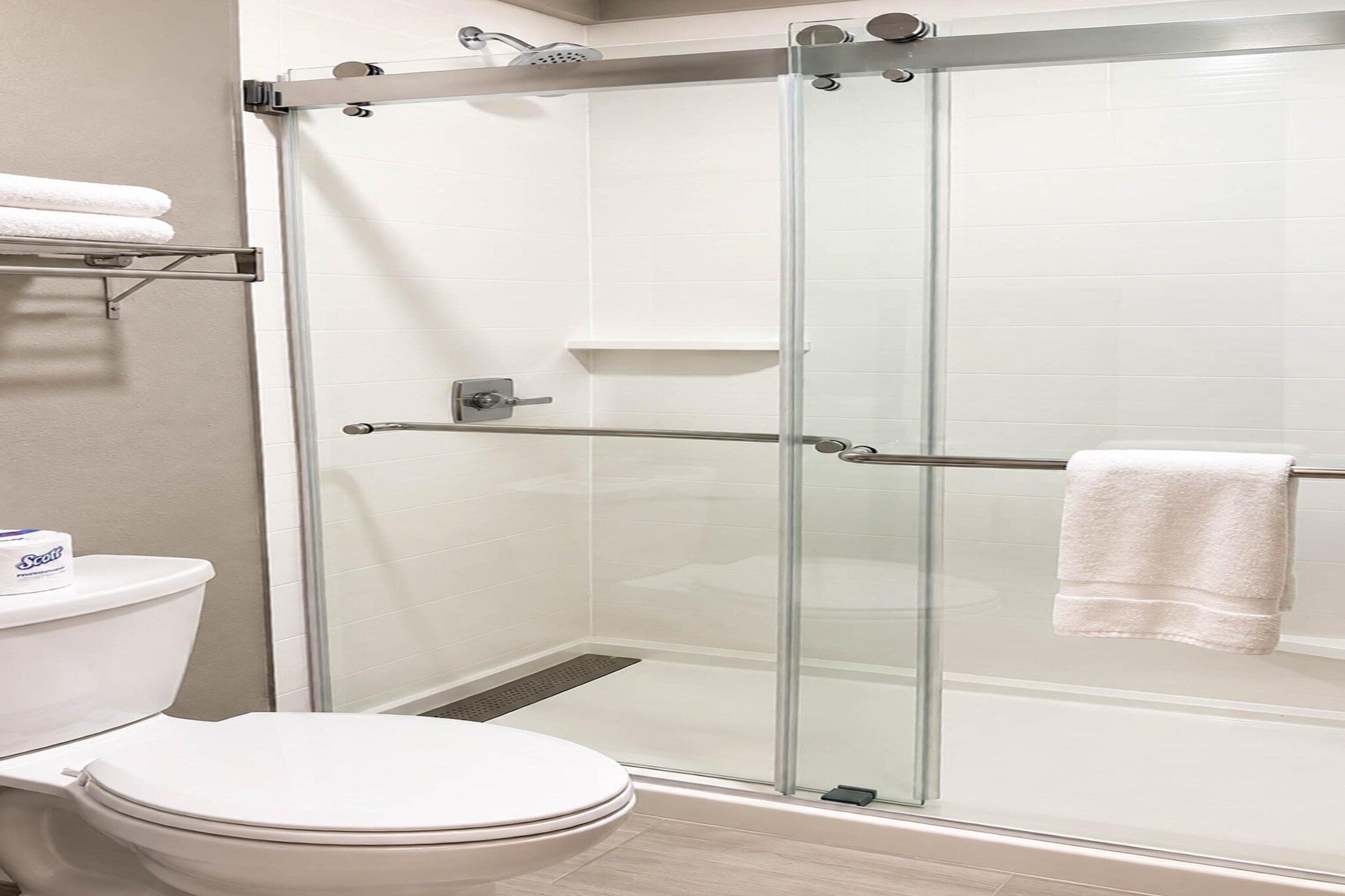 A bathroom with a glass-enclosed shower, a toilet, and a towel rack.