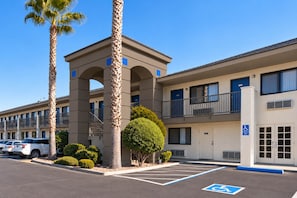 A multi-story building with a central tower, parking spaces, and a handicapped parking sign.