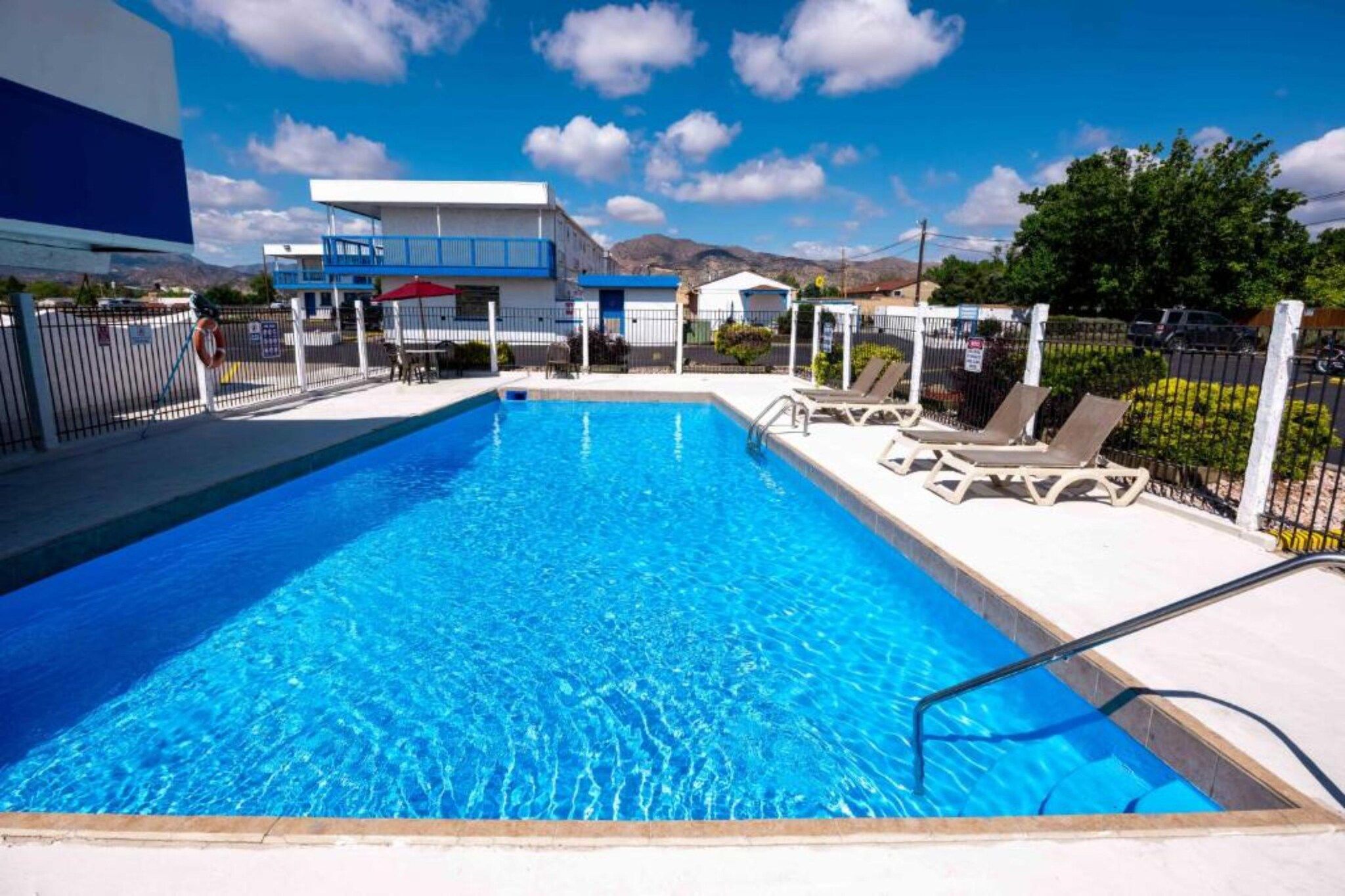 Una piscina con sillas de descanso, una silla de salvavidas y un edificio al fondo.