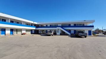 A two-story building with a flat roof and a parking lot in front.
