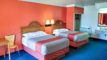 A hotel room with two beds, a desk, a chair, and a bathroom.