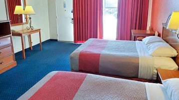 Una habitación de hotel con dos camas, un escritorio, una lámpara y un armario.