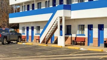Un motel con una hilera de habitaciones, una escalera y un estacionamiento.