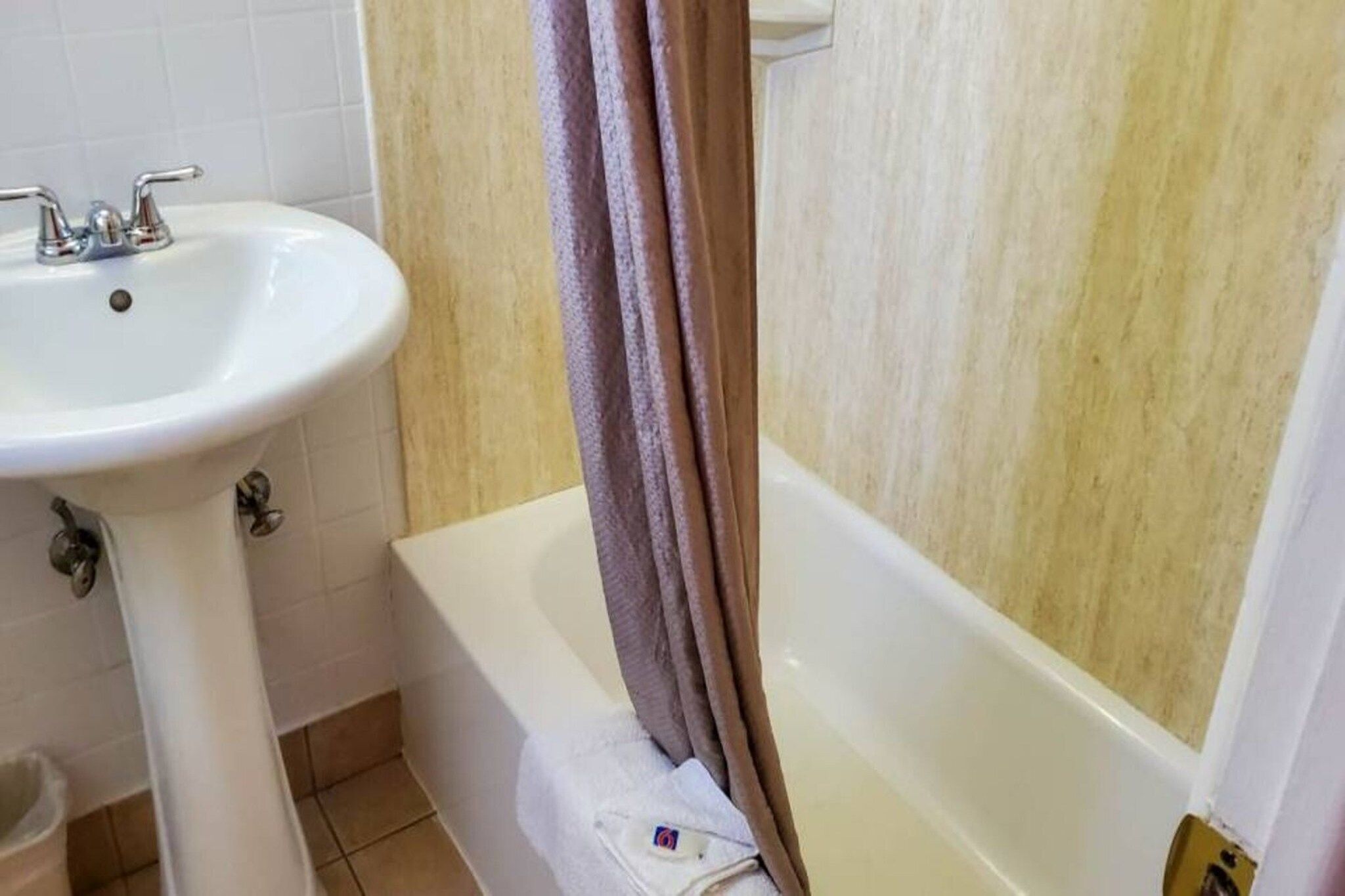 Un baño con lavamanos blanco, bañera y cortina de ducha.
