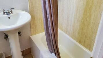 Un baño con lavamanos blanco, bañera y cortina de ducha.