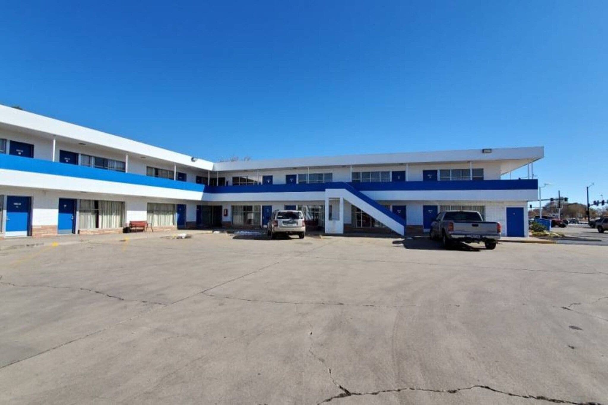 Un edificio de dos pisos con techo plano y un estacionamiento al frente.