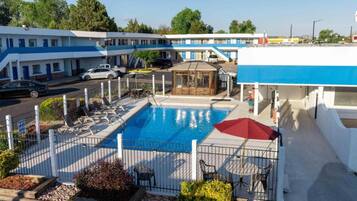 A hotel with a swimming pool, outdoor seating, and a view of the street.