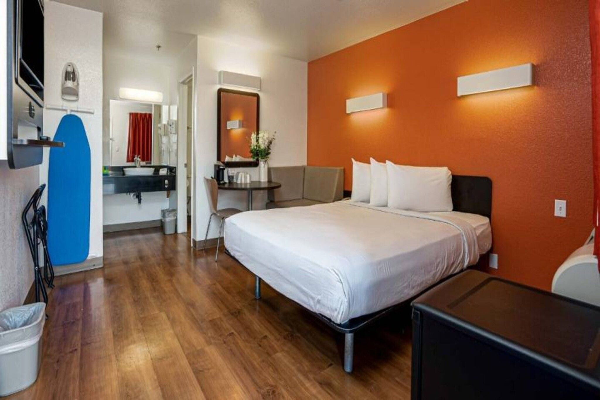 Een hotelkamer met een bed, een bureau, een stoel, een bijzettafeltje en een prullenbak.