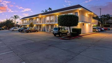 A motel with multiple rooms, a parking lot, and a small tree in front.