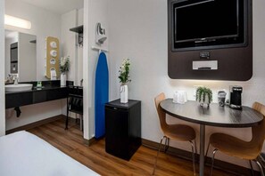 A hotel room with a bed, a desk with a coffee machine, a TV, and a small table with chairs. - 2 Full Beds | Non-Smoking (Temecula)