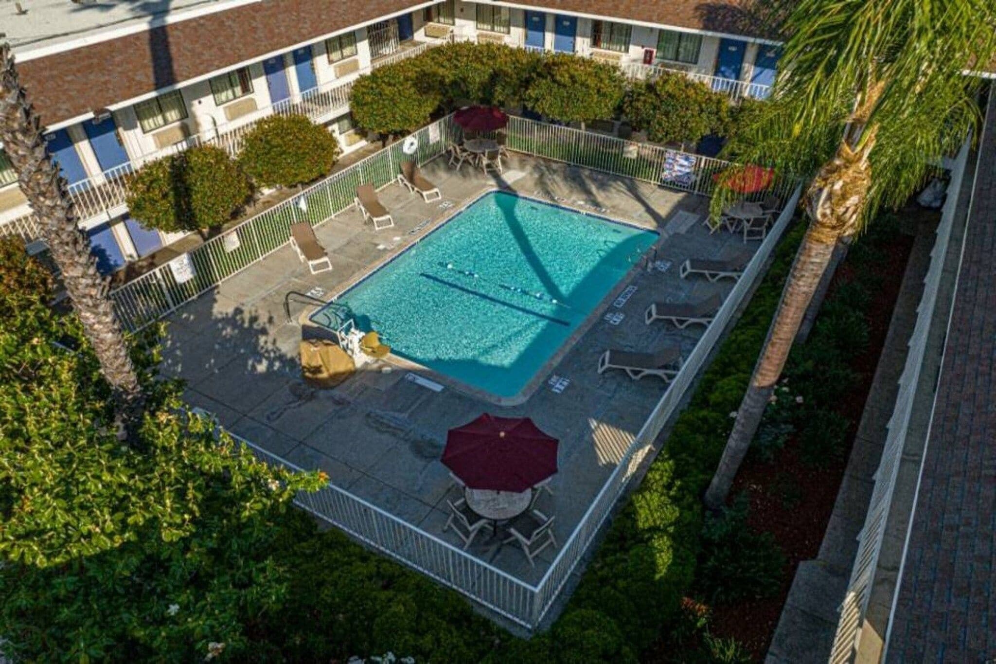 Vista aérea de um hotel com piscina, cercada por espreguiçadeiras e guarda-sóis.