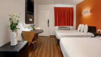 Een hotelkamer met een bed, een bureau, een stoel, een televisie en een raam met gordijnen.